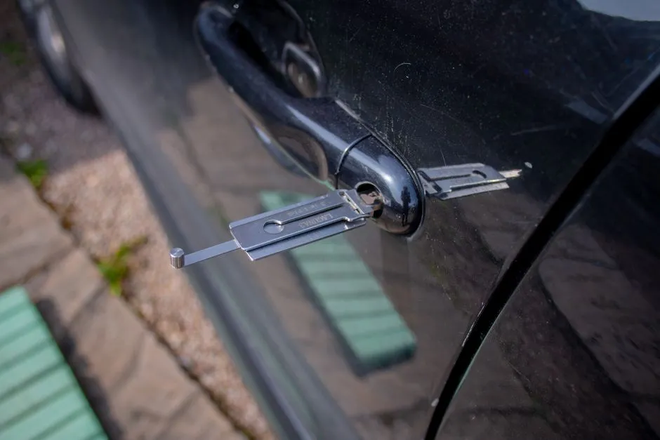 Locksmith tool inserted into a car door lock cylinder
